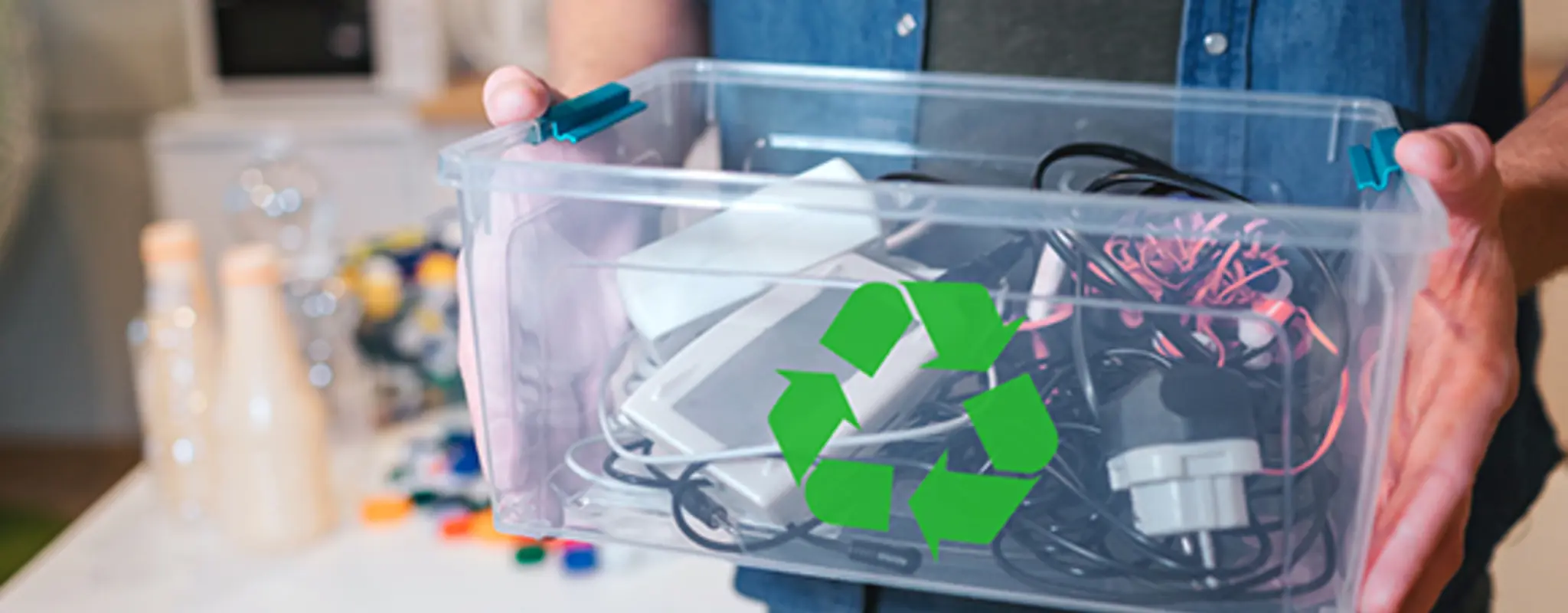 Ein Mann hält eine Kiste mit alten Elektrogeräten und Kabeln 