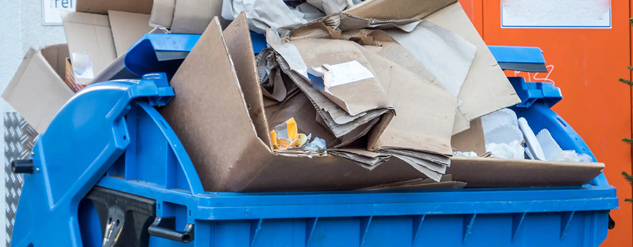 Ein überfüllter Altpapiercontainer vor einer Hausfassade