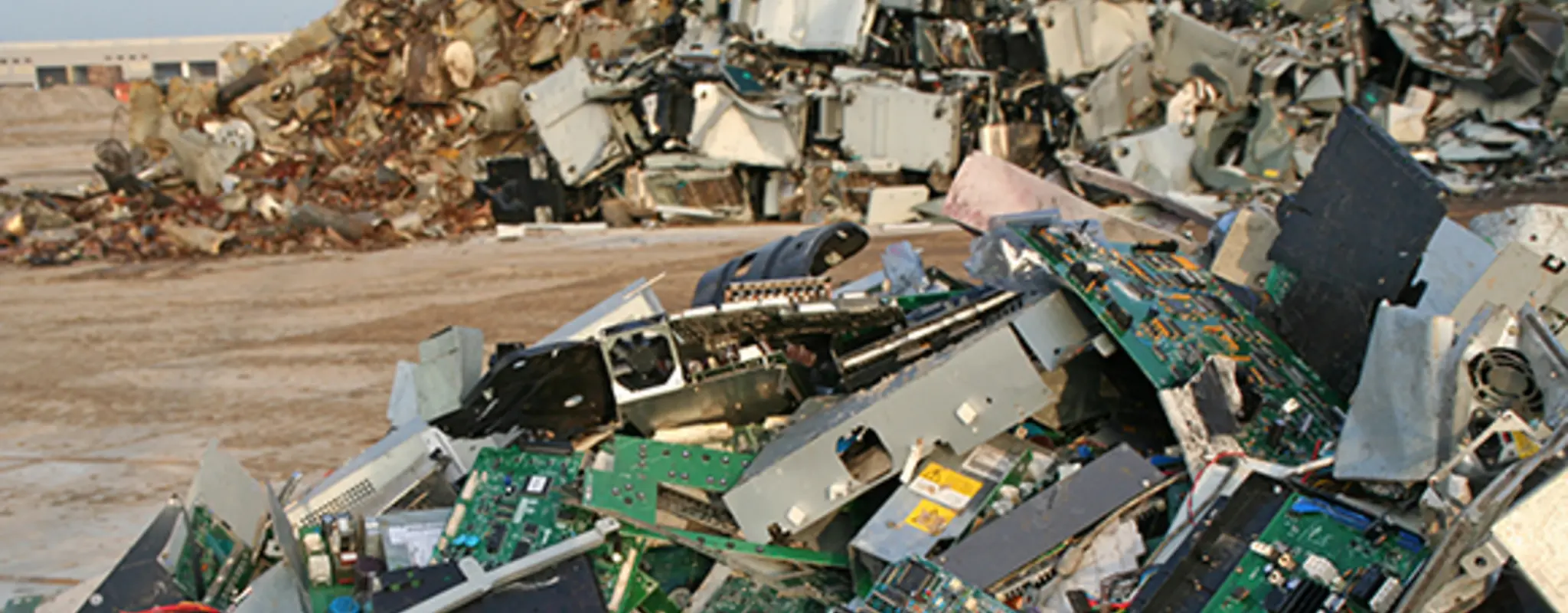 Berge von Elektronikabfällen auf einem sandigen Platz