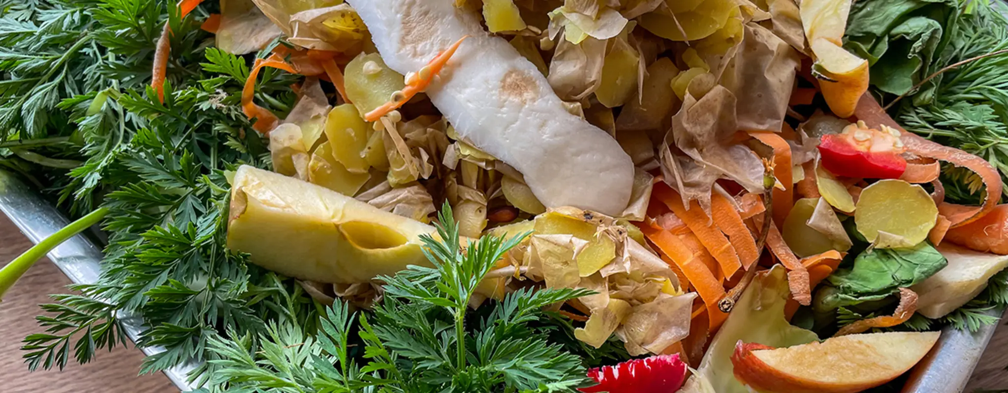 Essensabfälle wie Möhrengrün, Kartoffelschalen und Apfelkerngehäuse in einer Kiste