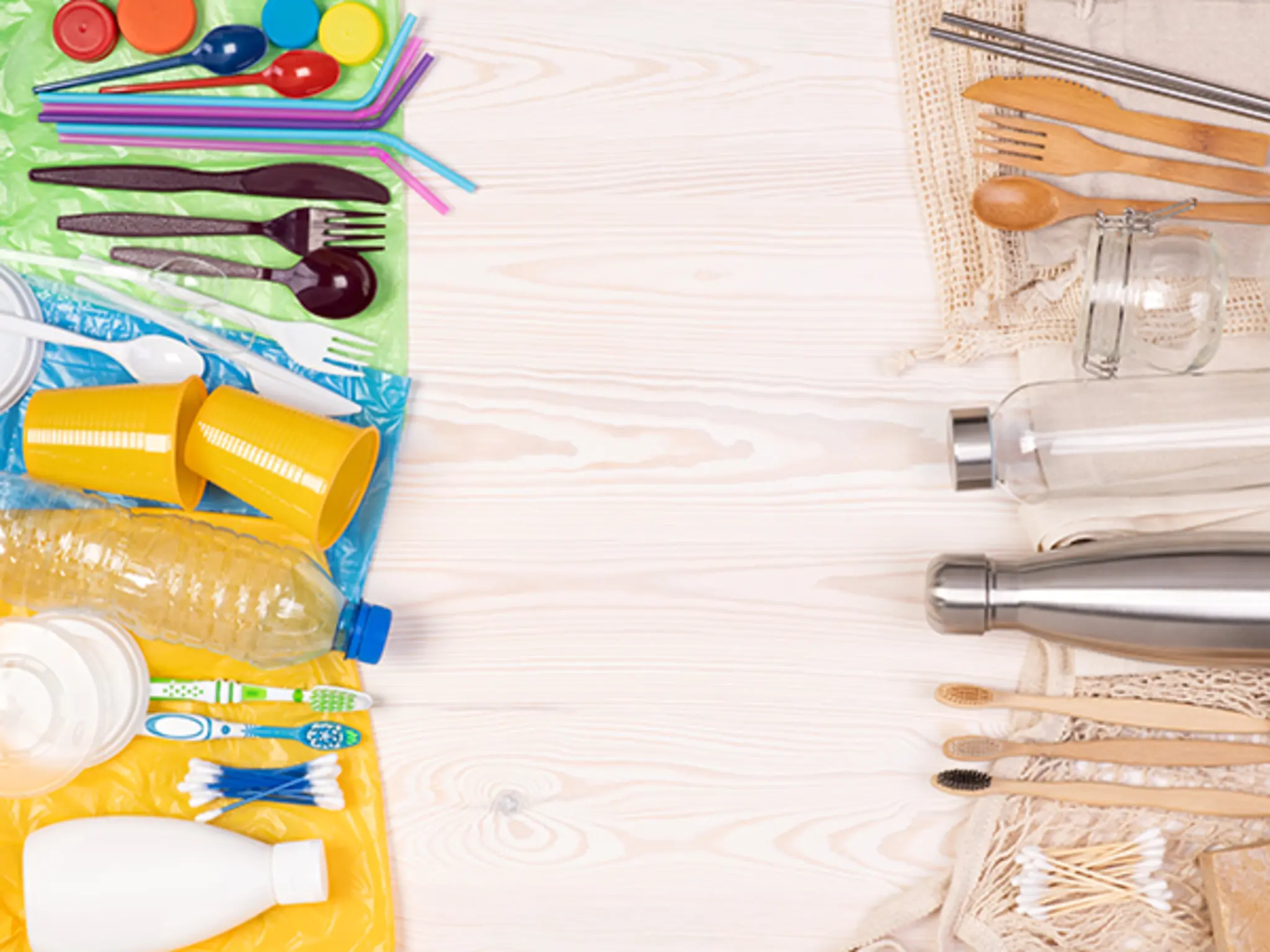 Plastikprodukte und nachhaltige Alternativen aus Metall, Holz, Glas und Bambus sind einander gegenüber auf einem Holzuntergrund drapiert: darunter Strohhalme, Besteck, Flaschen und andere Behältnisse, Zahnbürsten und Wattestäbchen