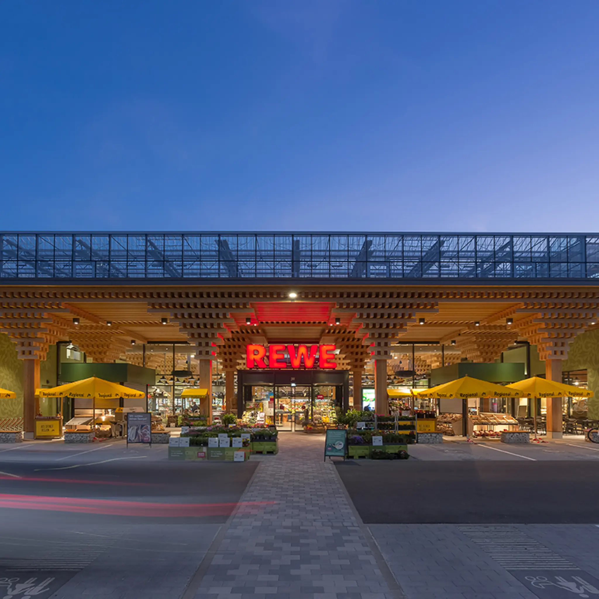 Der Eingang des Green Farming Marktes in Wiesbaden-Erbenheim. Als Baumaterial wurde viel Holz eingesetzt. Vor dem Markt stehen Stände mit Blumen und Pflanzen.
