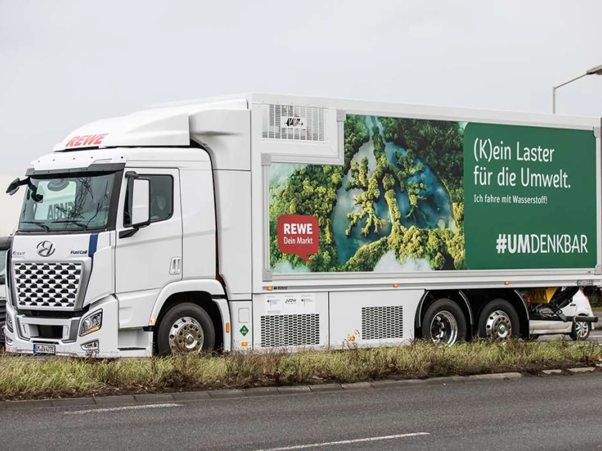 Ein Wasserstoff-Lkw vom Typ Hyundai XCIENT Fuel Cell. Auf der Seite steht „(K)ein Laster für die Umwelt. Ich fahre mit Wasserstoff! #UMDENKBAR“.