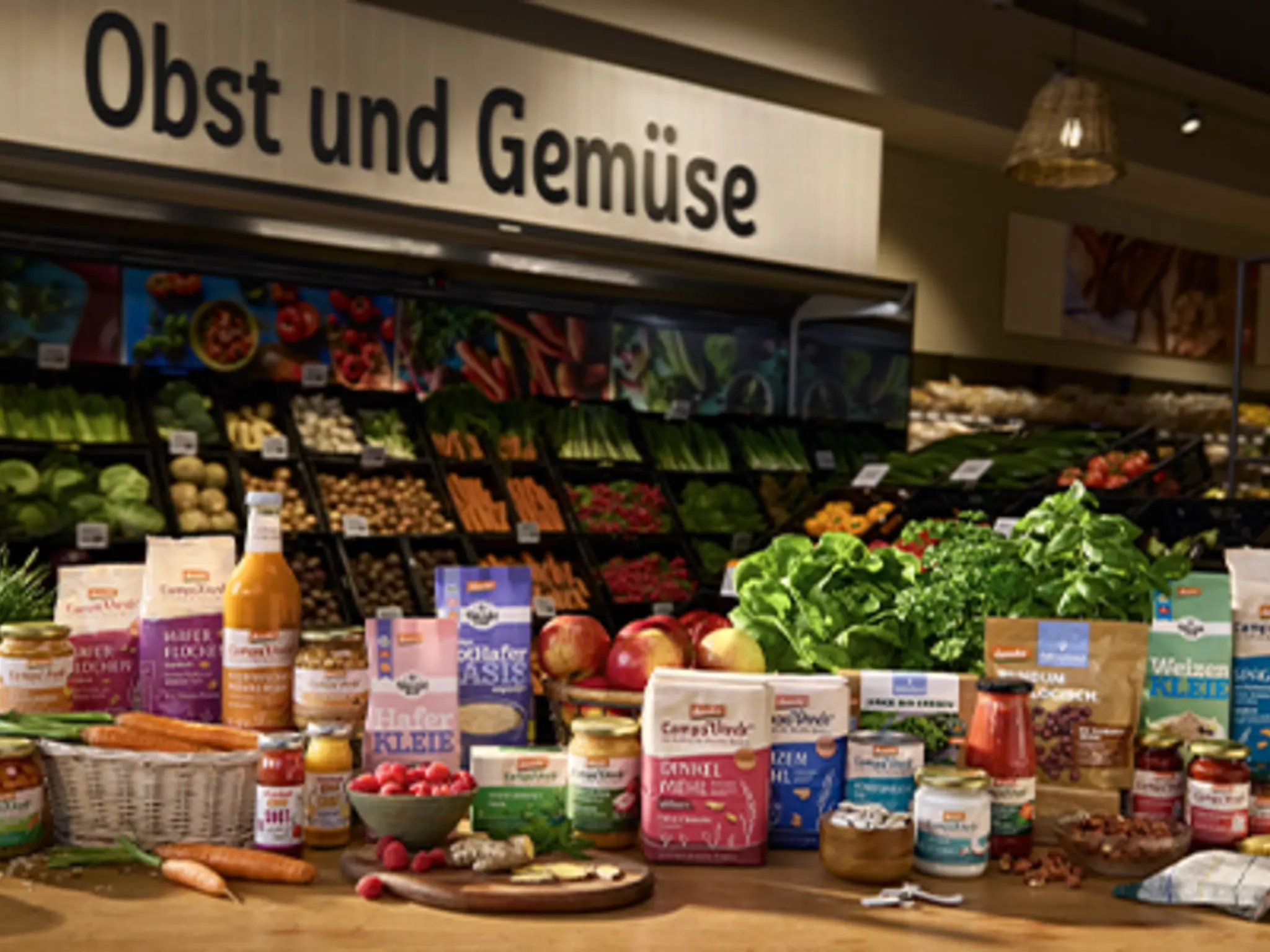 REWE Logo und demeter Logo mit Blumenwiese im Hintergrund