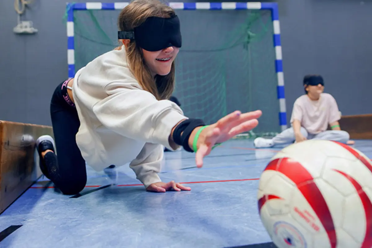 Ein Kind versucht mit verbundenen Augen, einen Ball zu greifen. 