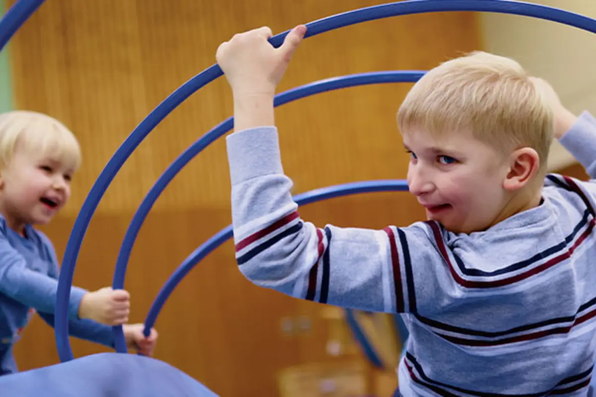 Zwei Kinder probieren spielerisch ein inklusives Turngerät aus. 