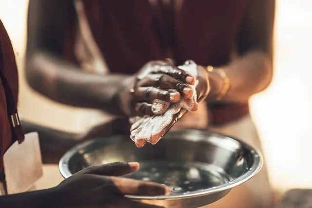 Zwei Personen waschen sich in einer Wasserschüssel die Hände mit Seife.