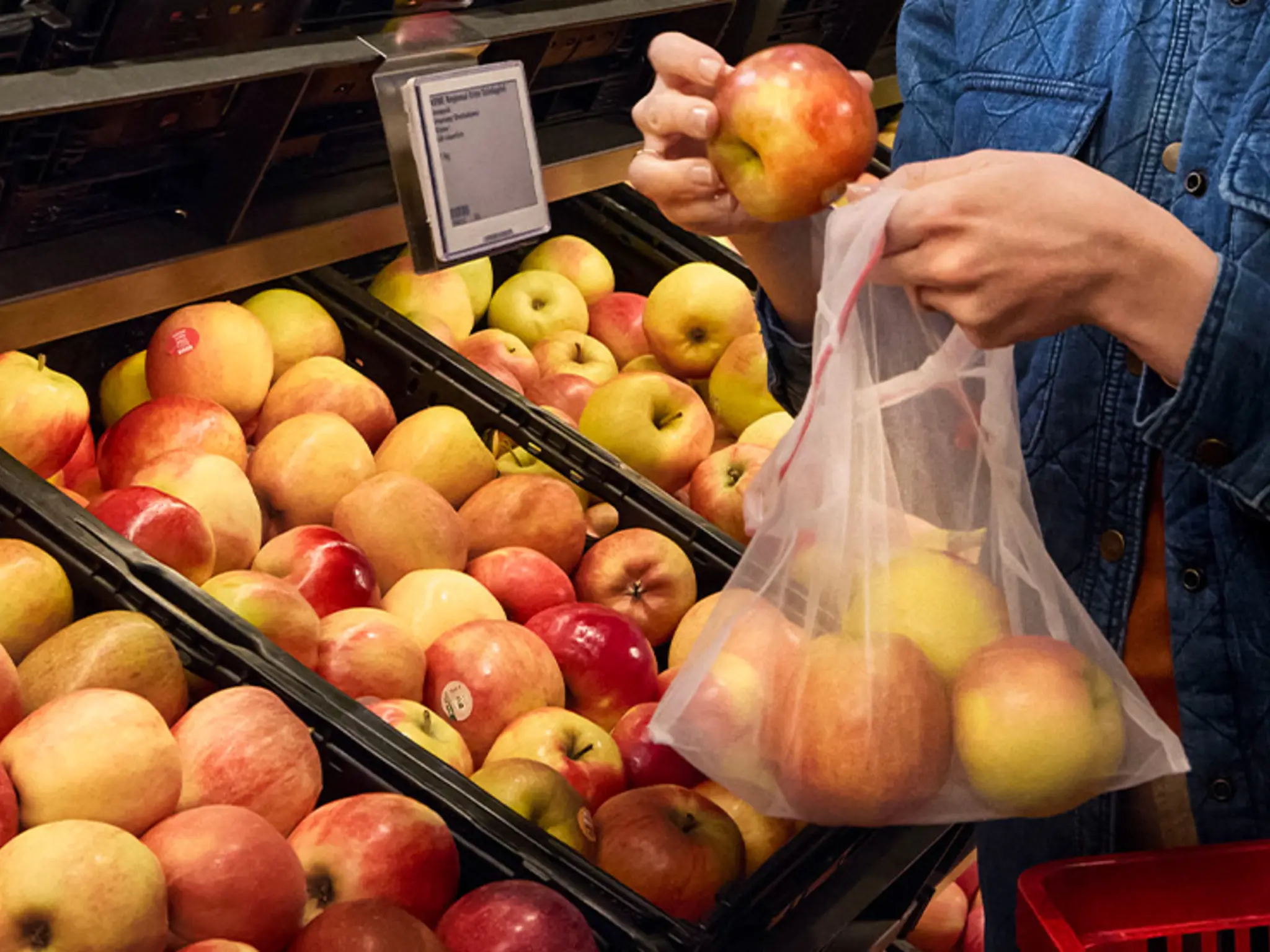Eine Person legt unverpackte Äpfel in ein Mehrweg-Frischenetz.