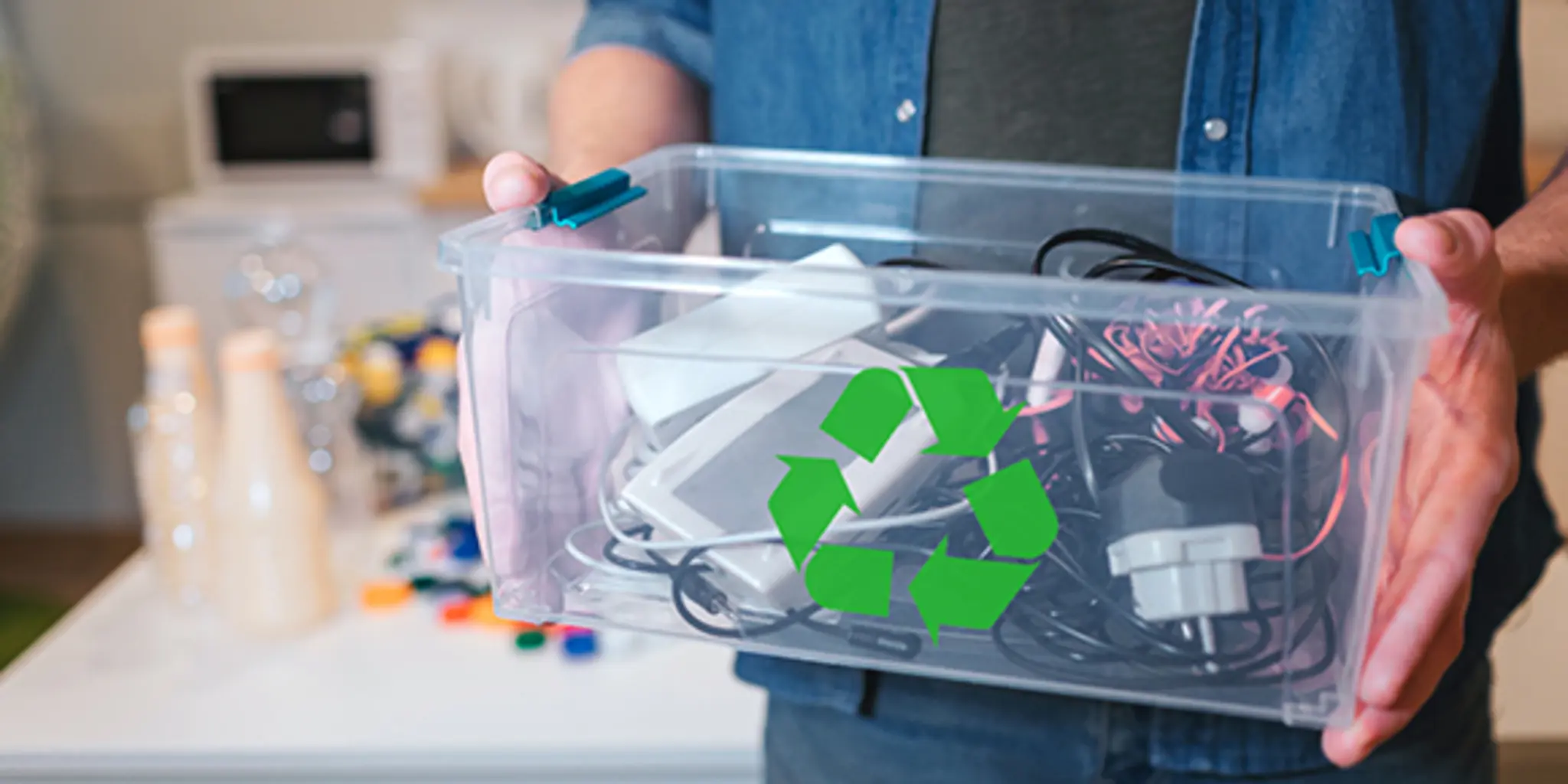 Ein Mann hält eine Kiste mit alten Elektrogeräten und Kabeln