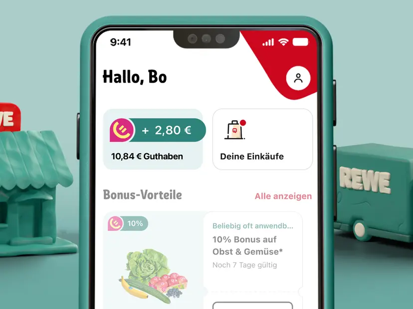 In einer illustrierten Fantasiewelt zeigt ein Smartphone die geöffnete REWE App mit REWE Bonus-Guthaben.