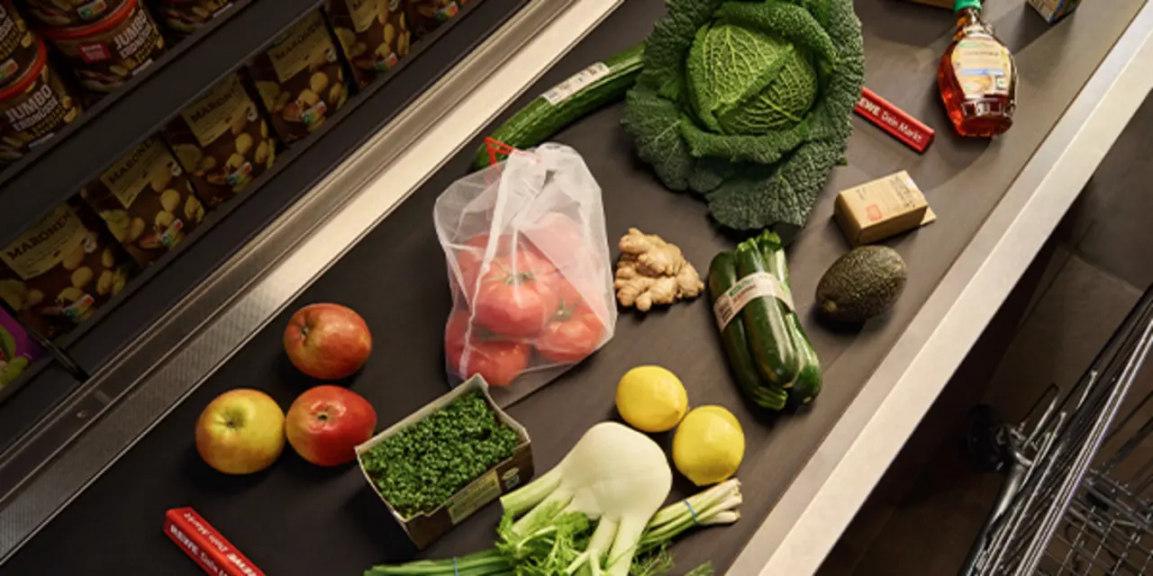 Verschiedene unverpackte Obst- und Gemüsesorten liegen auf einem Kassenband.
