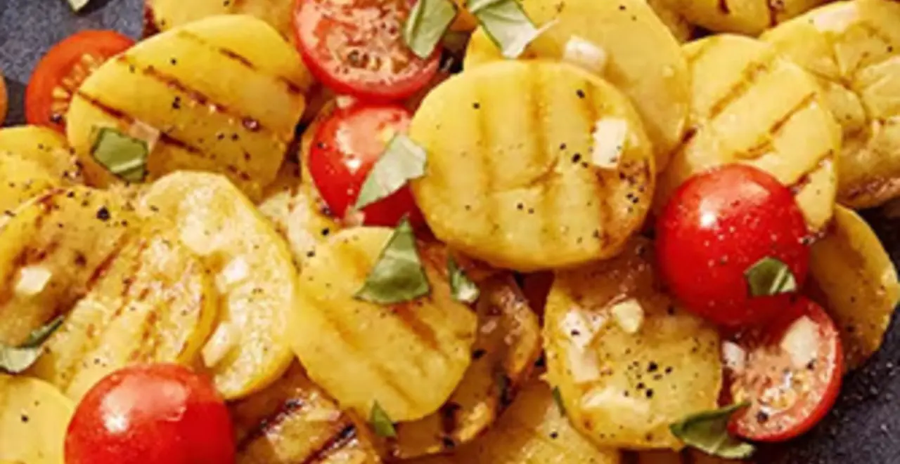 Ein Teller mit gegrilltem Kartoffelsalat steht auf einem Tisch.