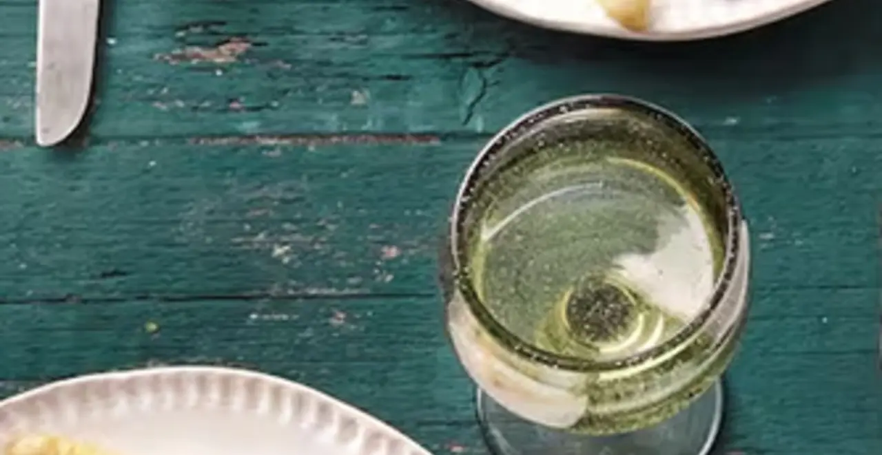 Eine großer Topf Kürbissuppe steht auf einem Tisch. Im Topf liegt eine Suppenkelle.