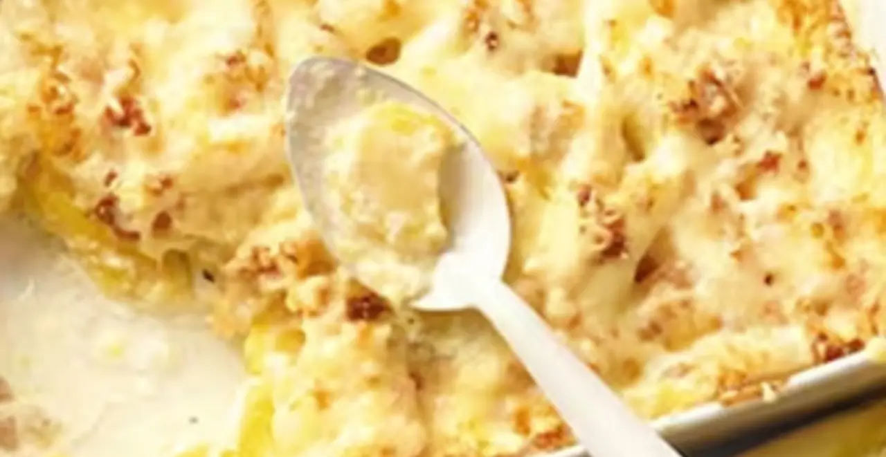 Eine Auflaufform mit Spargel und Kartoffeln. Um die Form sind die Zutaten und Teller mit dem Auflauf angerichtet