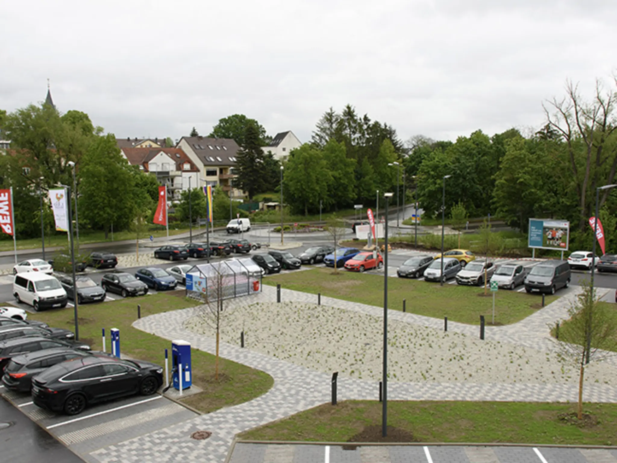 Ein Blick von schräg oben auf den Parkplatz des Green Farming Marktes. Dank der Grünflächen kann Regenwasser versickern.