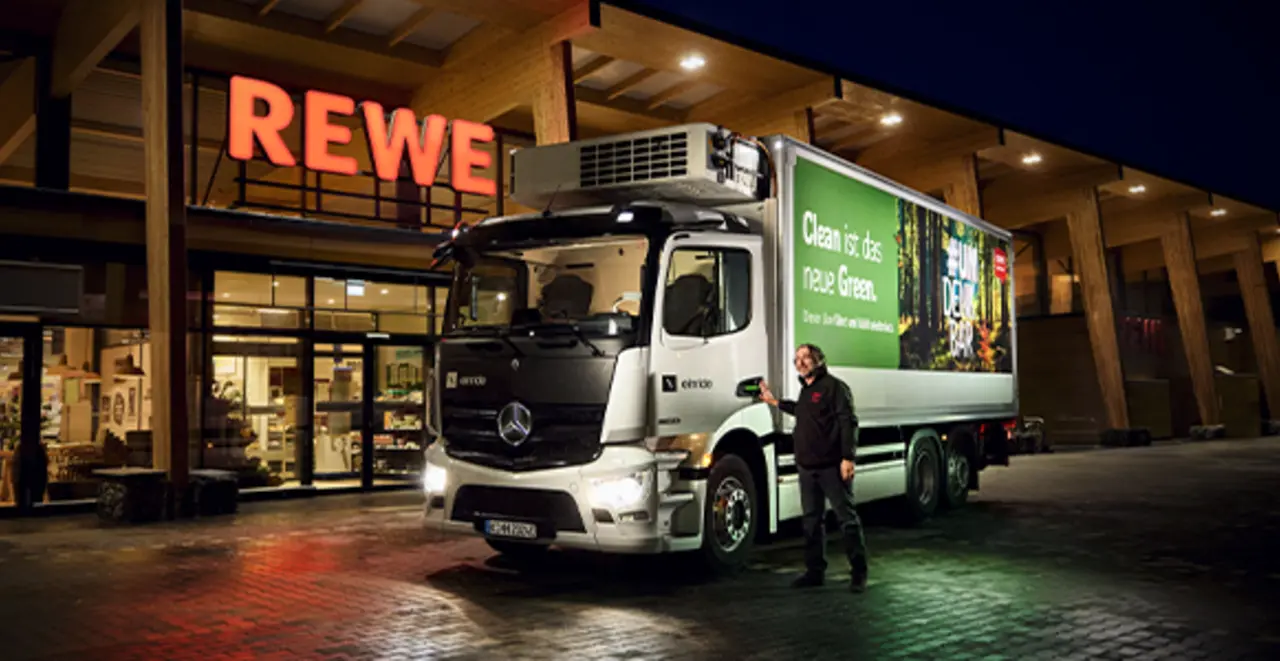 Ein moderner REWE e-Lkw vor einem nachhaltigeren REWE Green Building.
