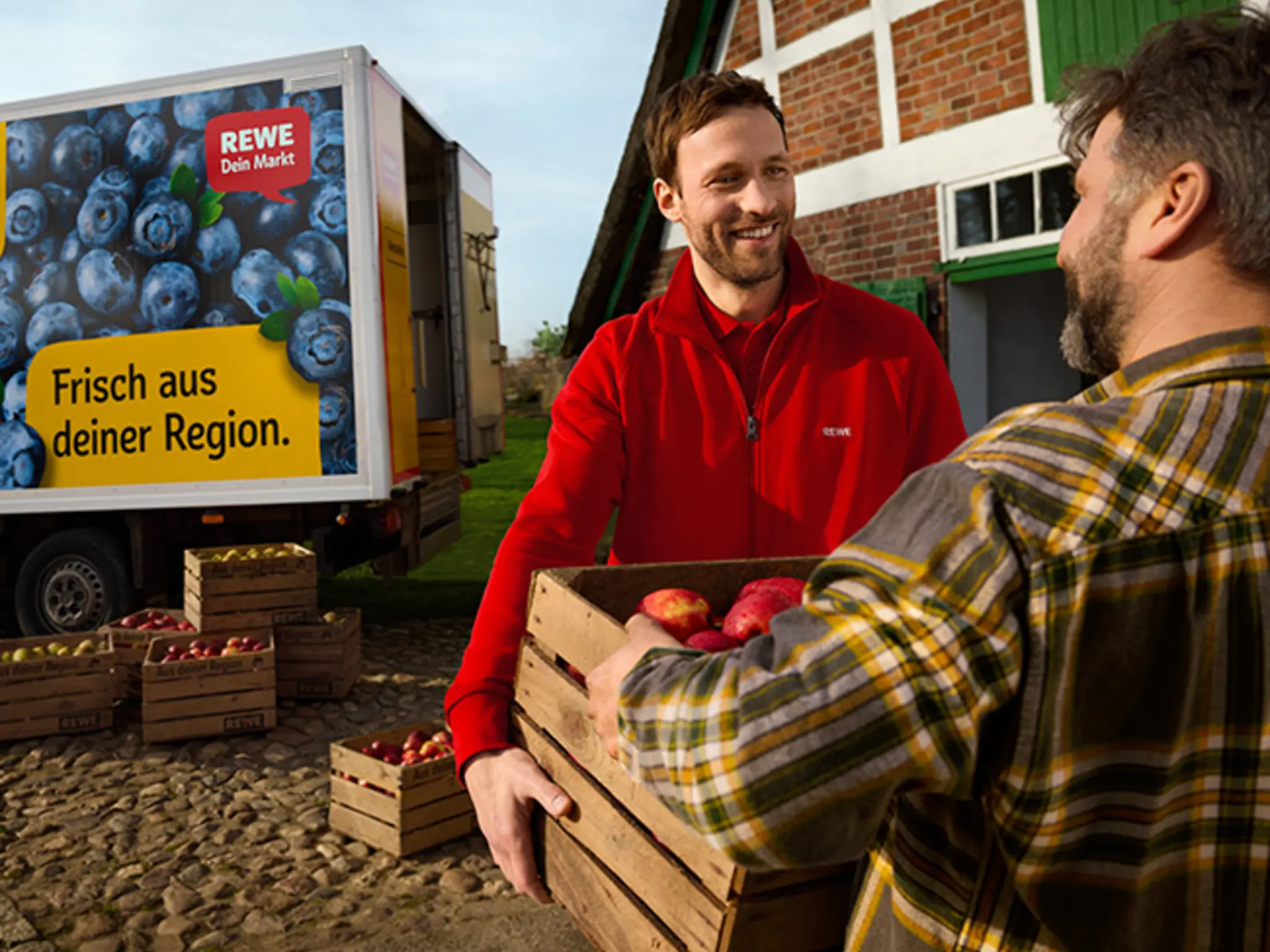 Ein Fahrzeug des REWE Lieferservice holt regionale Äpfel direkt auf dem Bauernhof ab. Die Darstellung vermittelt: Erntefrische Produkte kommen aus deiner Nachbarschaft direkt zu dir. 