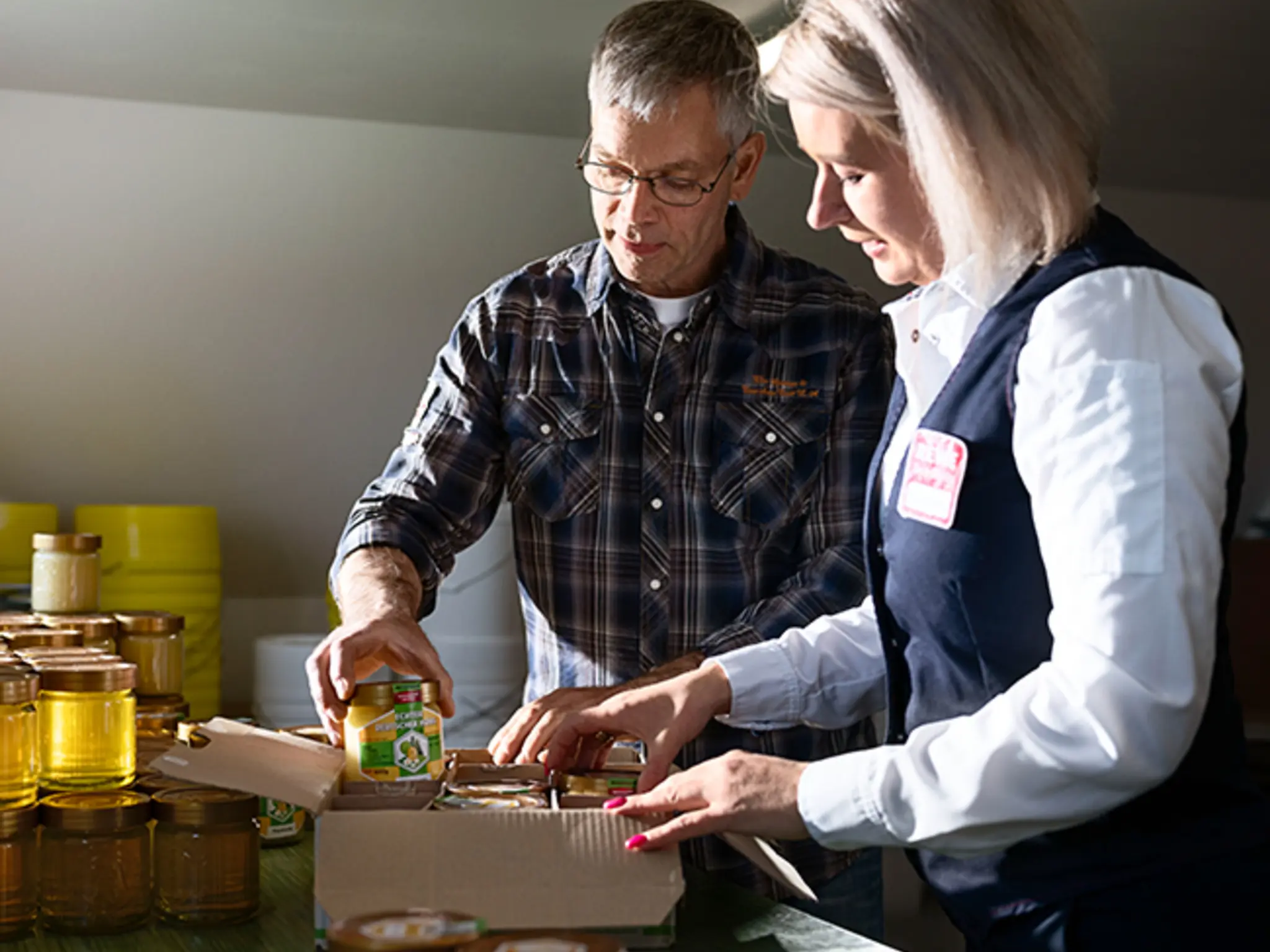 Jan Fischer und Olga Berg auf einer Obstwiese. Jan holt eine Honigwabe aus einem Bienenstock.