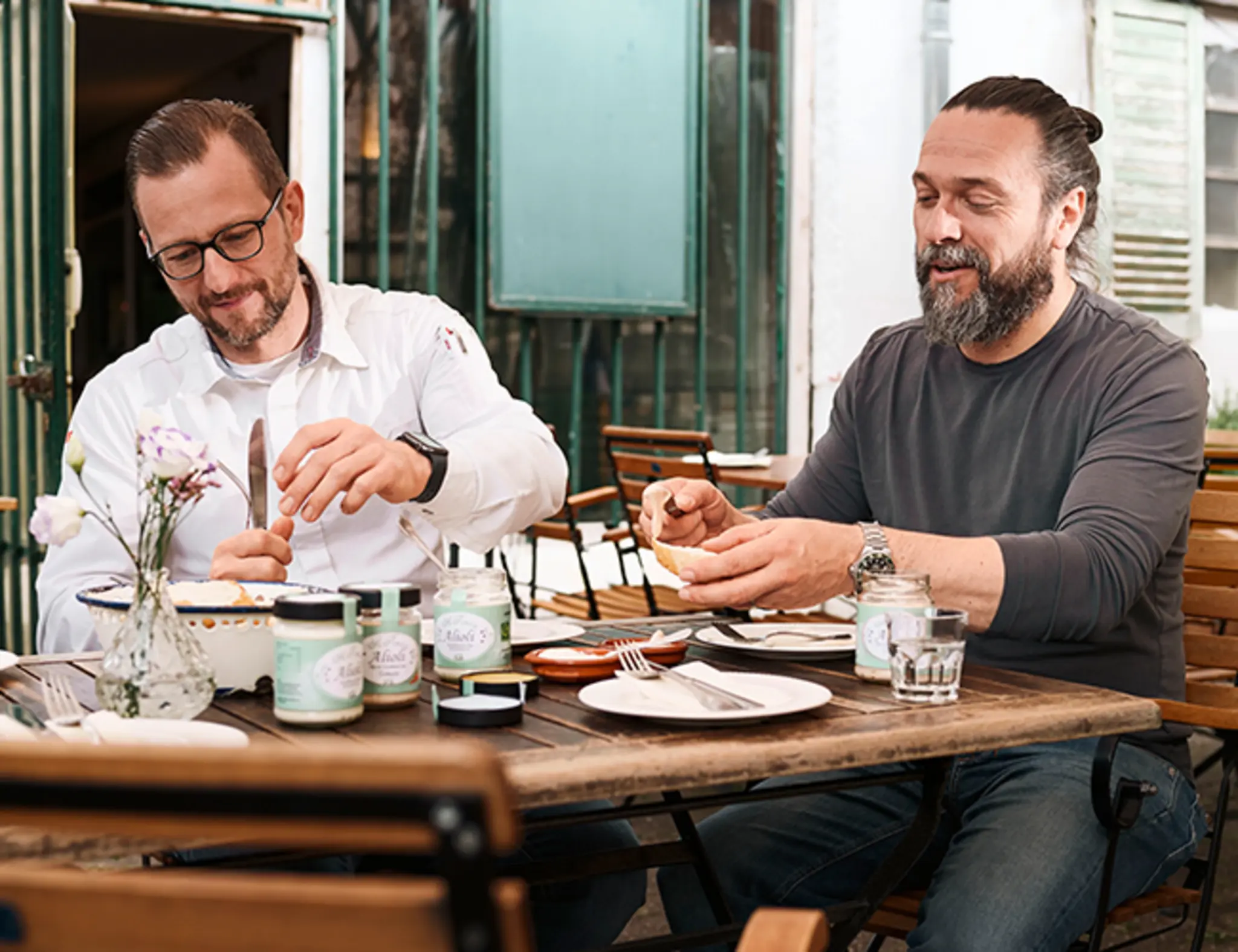 REWE Kaufmann Andre Becker und Lokal-Partner Robert Buljat essen gemeinsam Aioli mit Brot. 