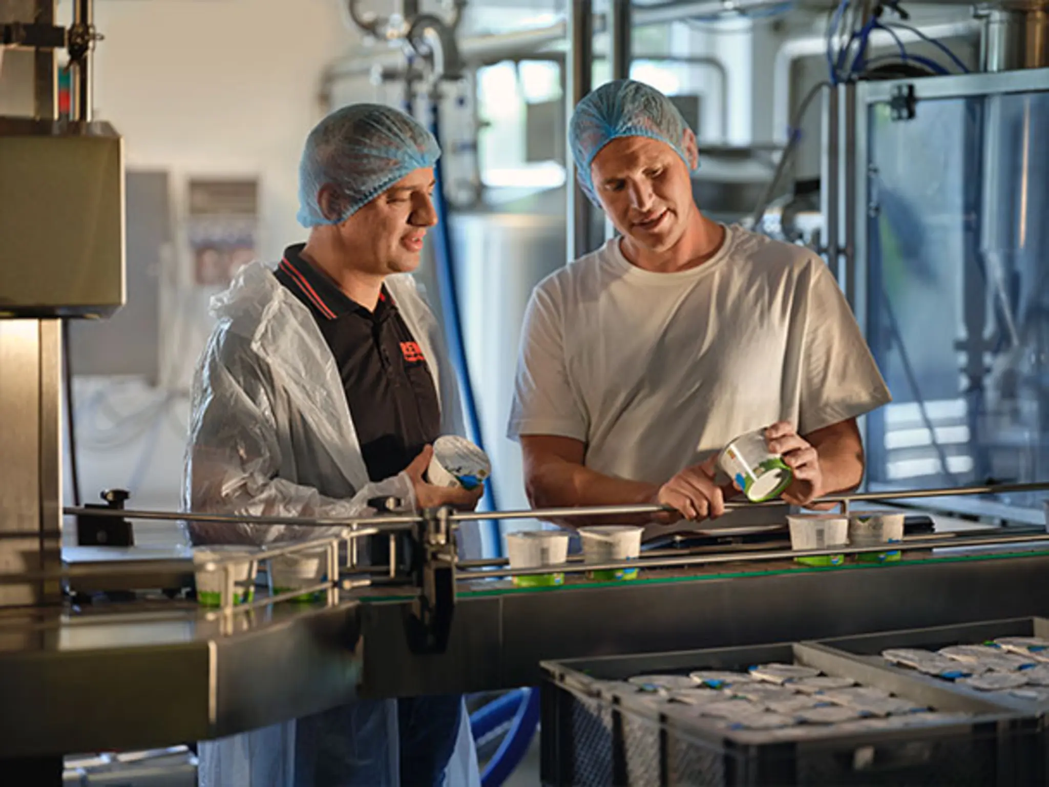 David Engel und Wladimir Pojanov in der Molkerei des Engelshofs. Die beiden betrachten die hofeigenen Produkte im Becher.
