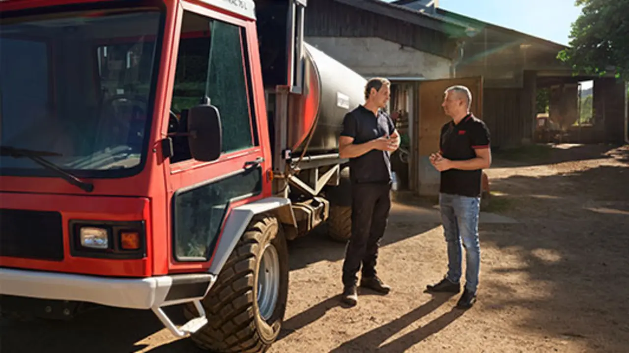 Landwirt David Engel und REWE Kaufmann Wladimir Pojanow vor einem Molkereiwagen im Gespräch. 
