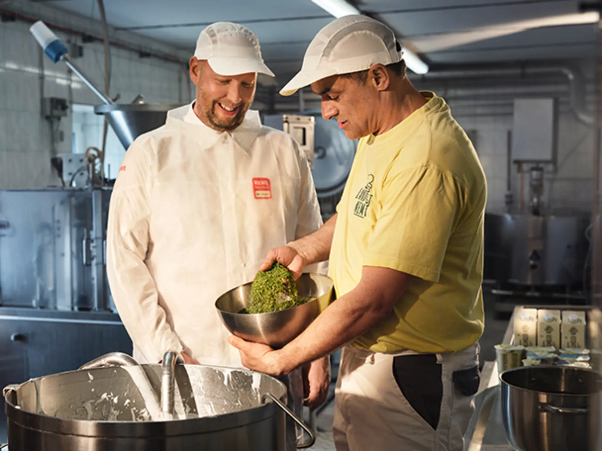 Landwirt Karsten Döbelt zeigt REWE Kaufmann Ricco Hahn, wie in der Molkerei seines Landguts frischer Quark hergestellt wird.