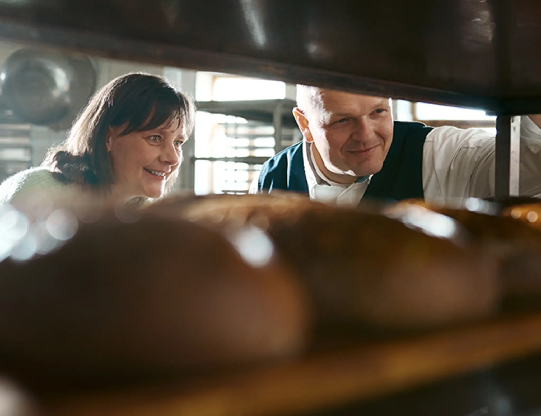 Sophia Sucholas und Björn Keyser betrachten frische Brote in der Bäckerei.
