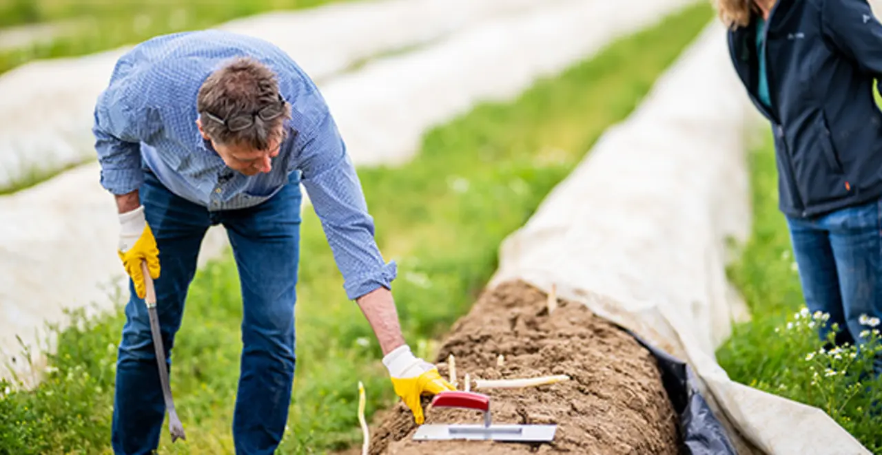 Ein Naturland Mitarbeiter und eine Landwirtin auf dem Feld. Sie prüfen den Boden. 