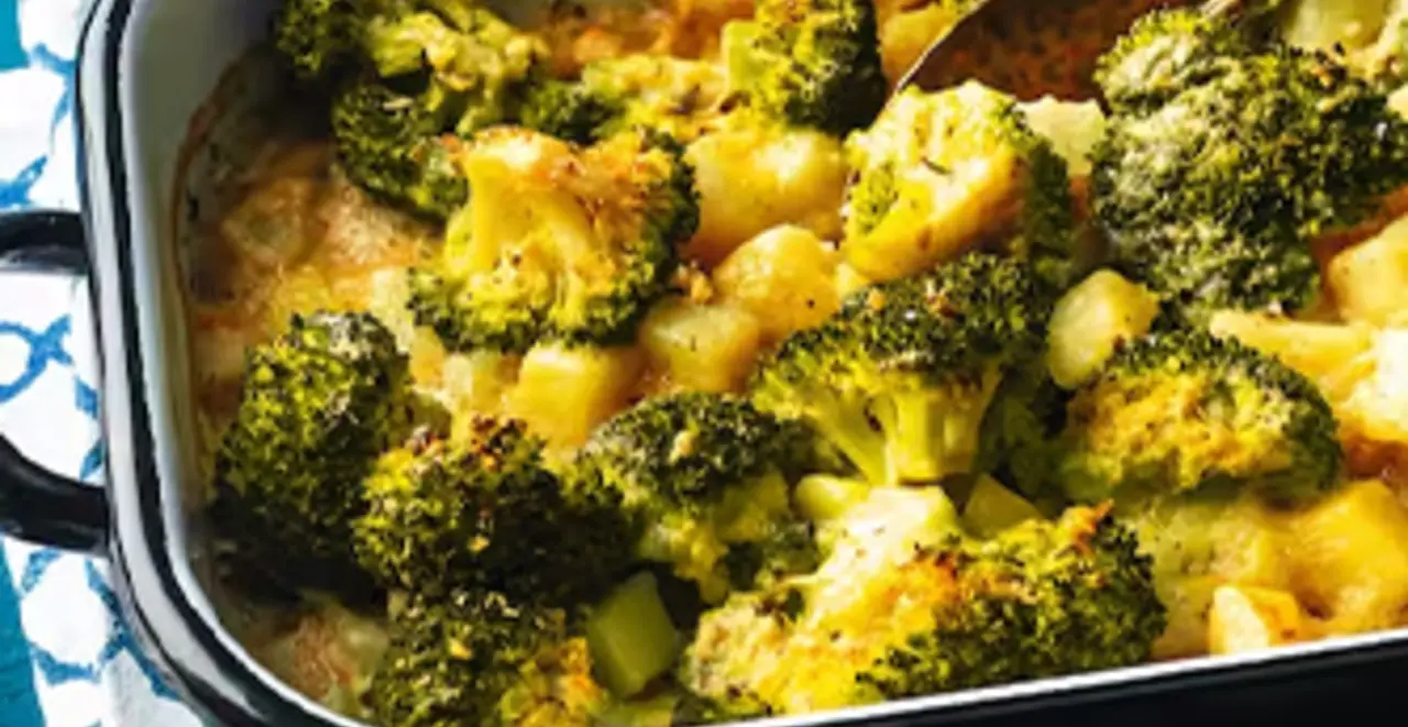 Eine Form mit veganem Kartoffel-Brokkoli-Auflauf steht auf einem gedeckten Tisch.