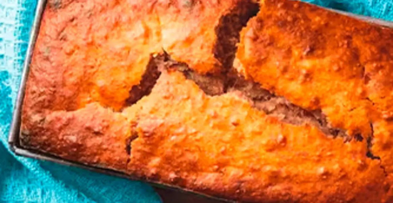 Ein frisch gebackenes veganes Bananenbrot steht auf einem gedeckten Kaffeetisch.