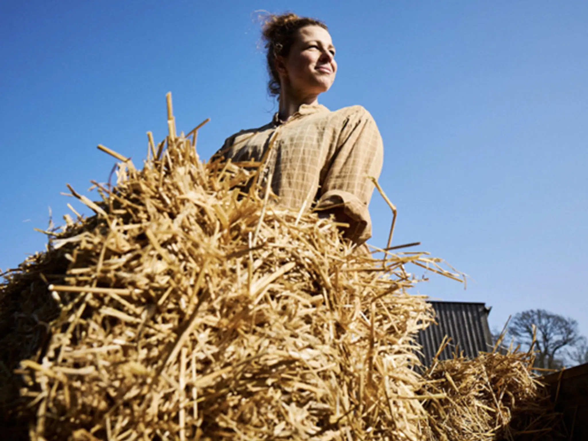 Landwirtin hebt Heu an im Sonnenschein