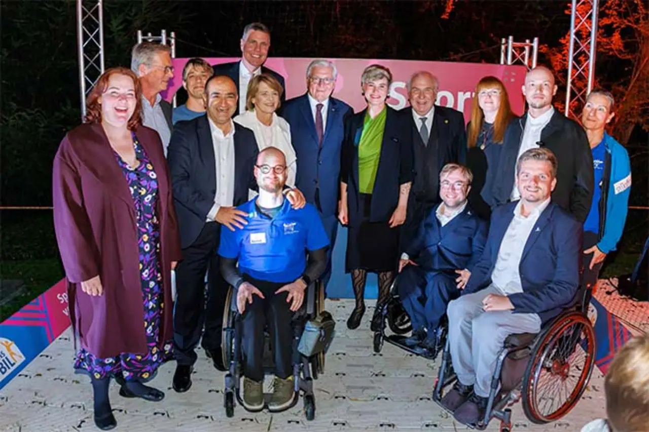 Gruppe von Erwachsenen, darunter drei Personen im Rollstuhl, posiert gemeinsam auf einer Bühne beim Bürgerfest. Copyright: DBS