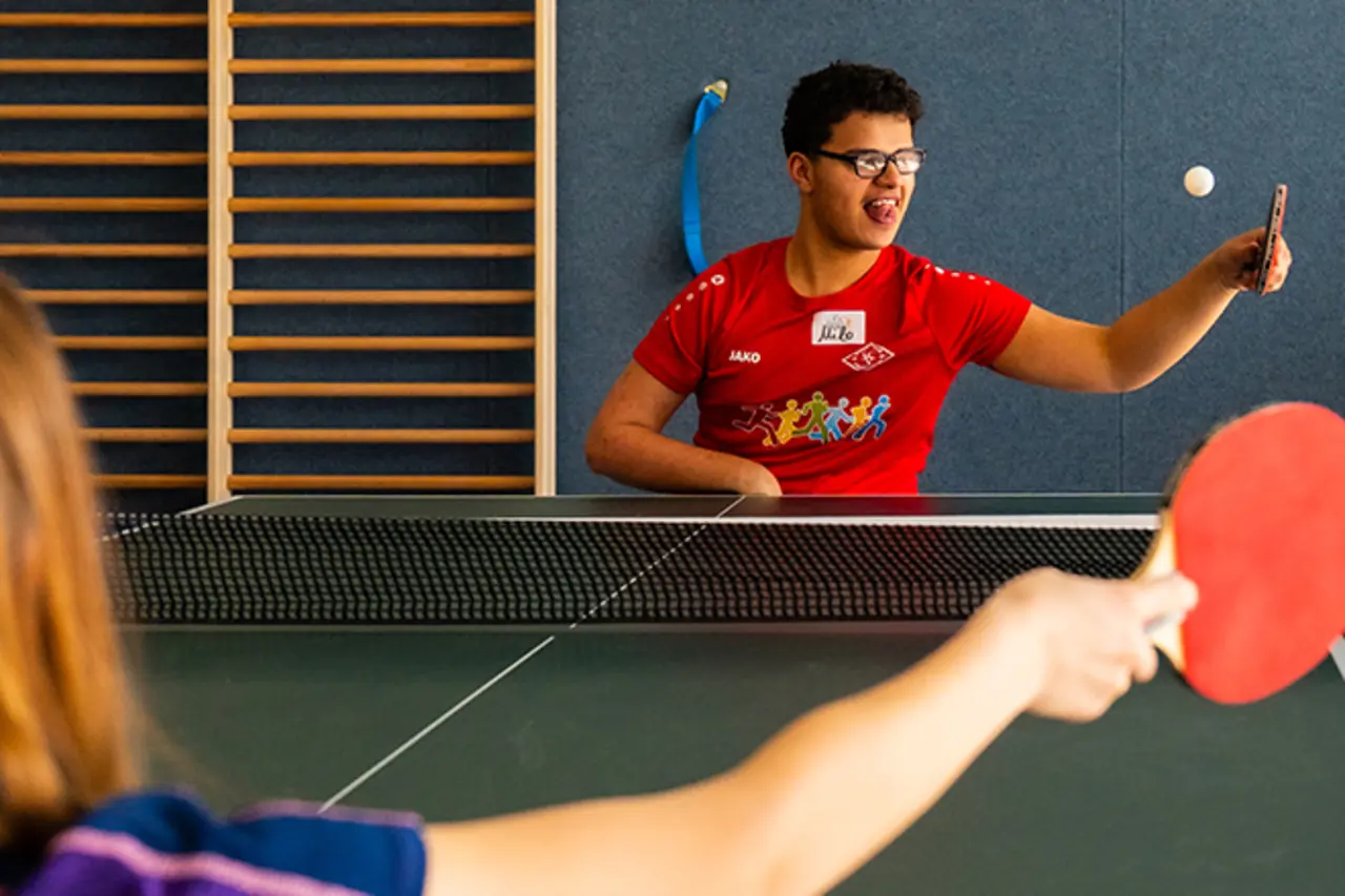 Zwei Jugendliche mit und ohne Behinderung spielen gemeinsam Tischtennis.