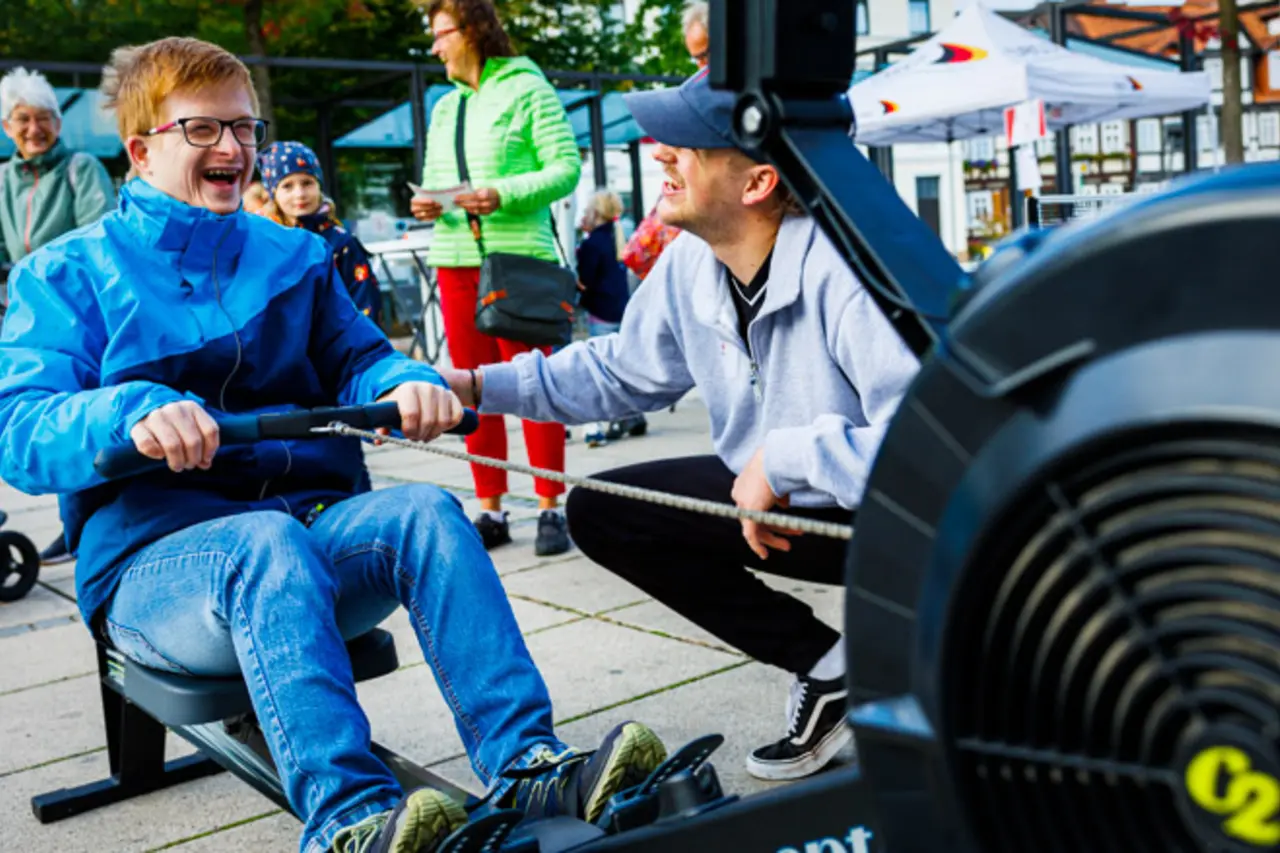 Ein Mensch mit Behinderung probiert eine inklusive Rudermaschine aus.