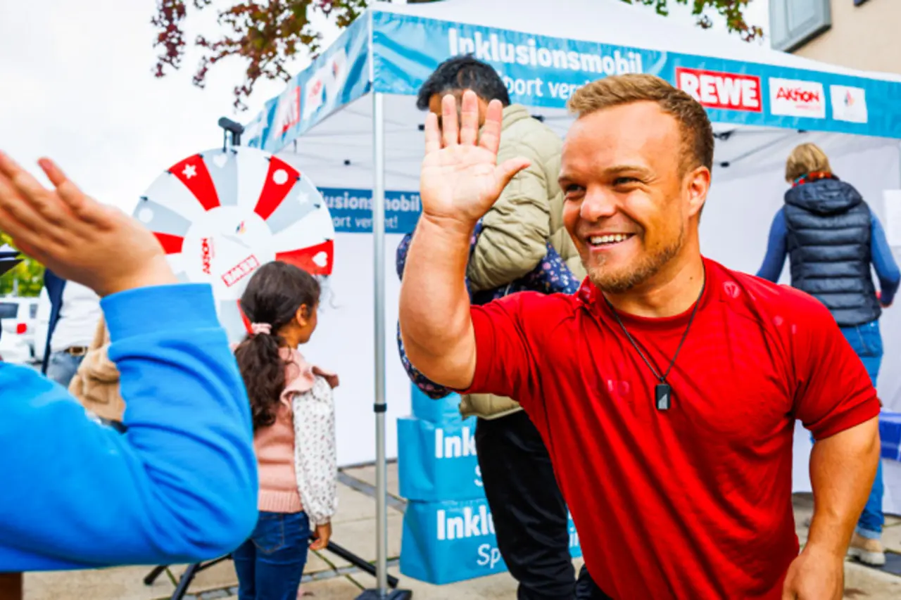 Para-Kugelstoßer Niko Kappel gibt einem Jungen High Five.