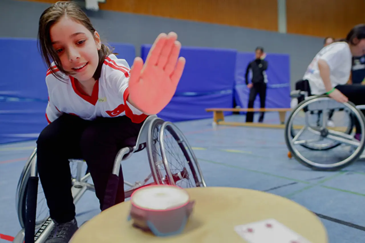 Ein Mädchen im Rollstuhl schlägt auf einen Buzzer.