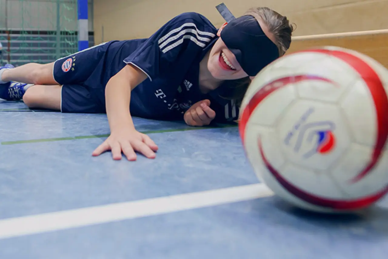 Ein Kind versucht, mit verbundenen Augen einen Handball zu fangen.
