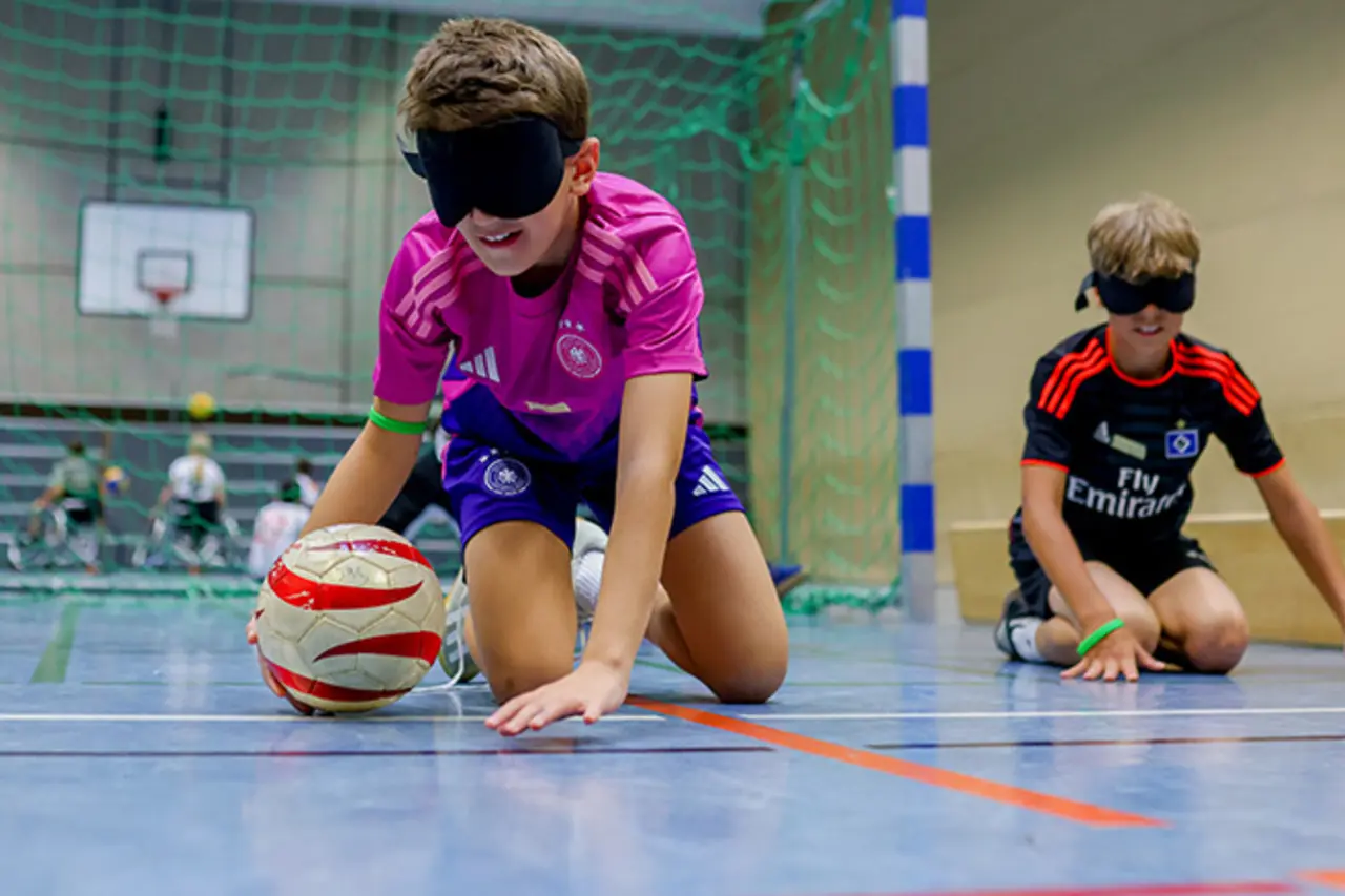Ein Kind sitzt mit verbundenen Augen im Handballtor.