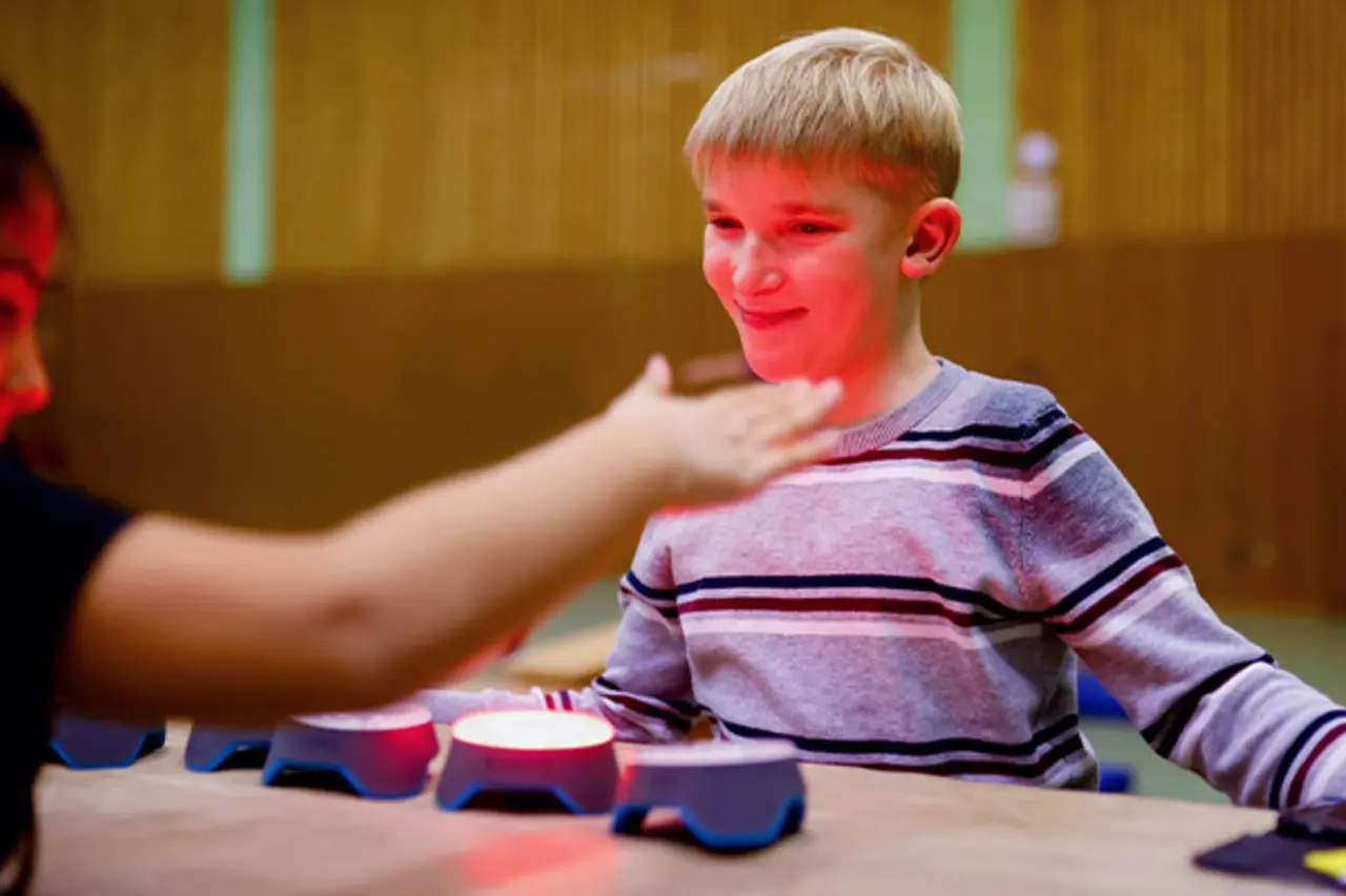 In der Halle des TV Ratingen. Zwei Kinder sitzen an einem Tisch und machen ein Geschicklichkeitsspiel.