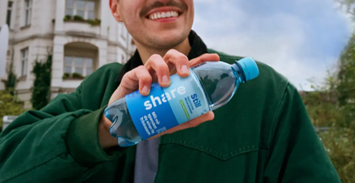 Eine Person hält eine Flasche share stilles Wasser.