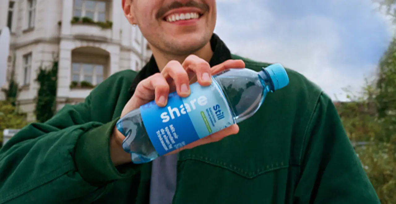 Eine Person hält eine Flasche share stilles Wasser.