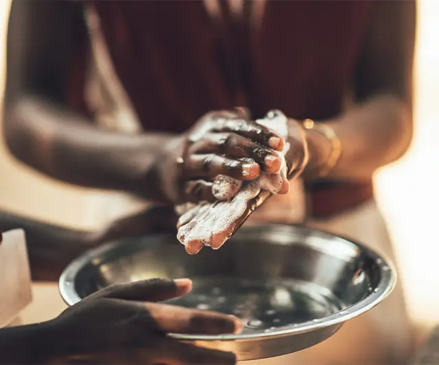 Zwei Personen waschen sich in einer Wasserschüssel die Hände mit Seife.