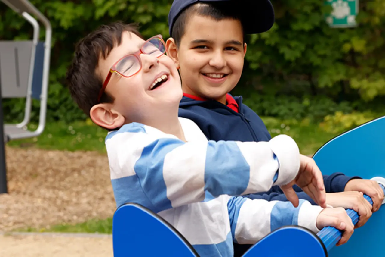 Kinder mit und ohne Behinderung fahren zusammen Karussell. 