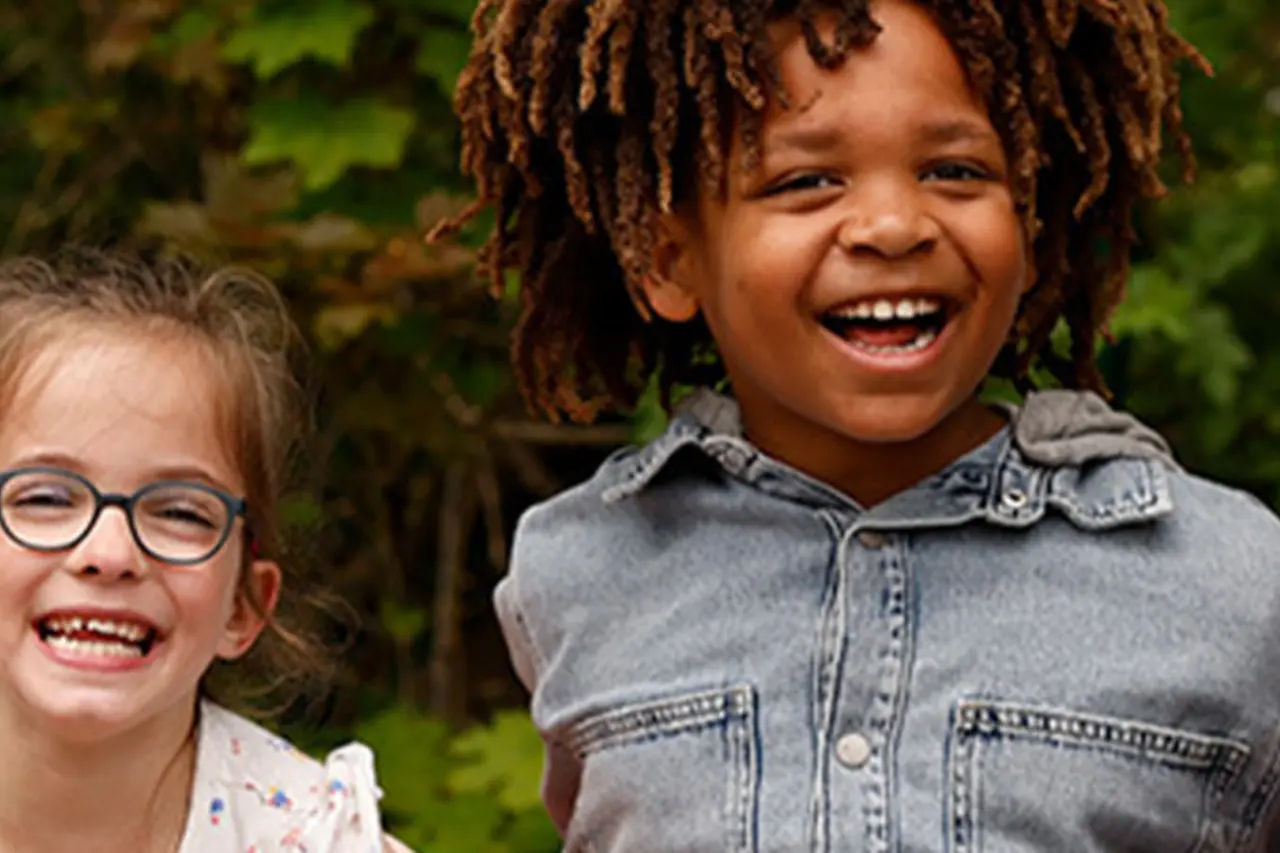 Zwei Kinder sitzen auf einem inklusiven Klettergerüst. Eines von ihnen trägt eine Beinprothese. 