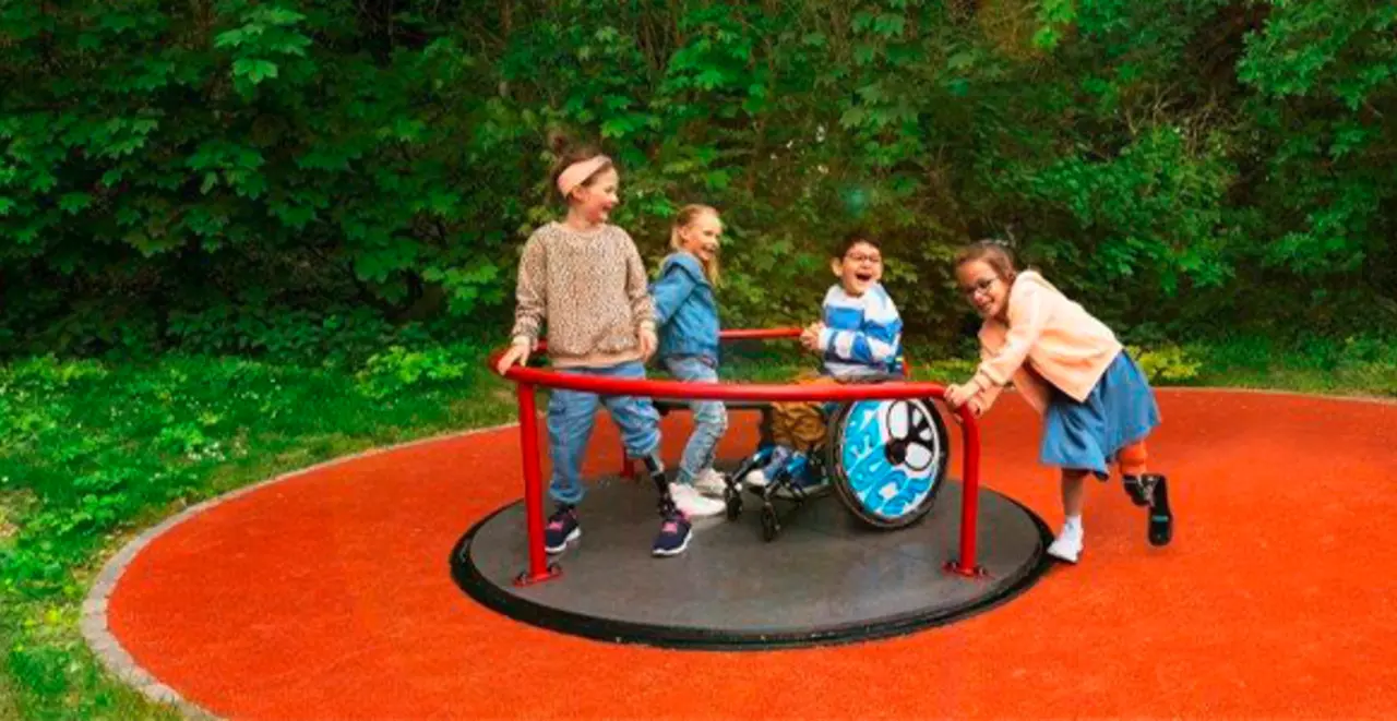 Kinder mit und ohne Behinderung spielen gemeinsam auf einem Universal Karussell mit ebenerdigem Zugang. 