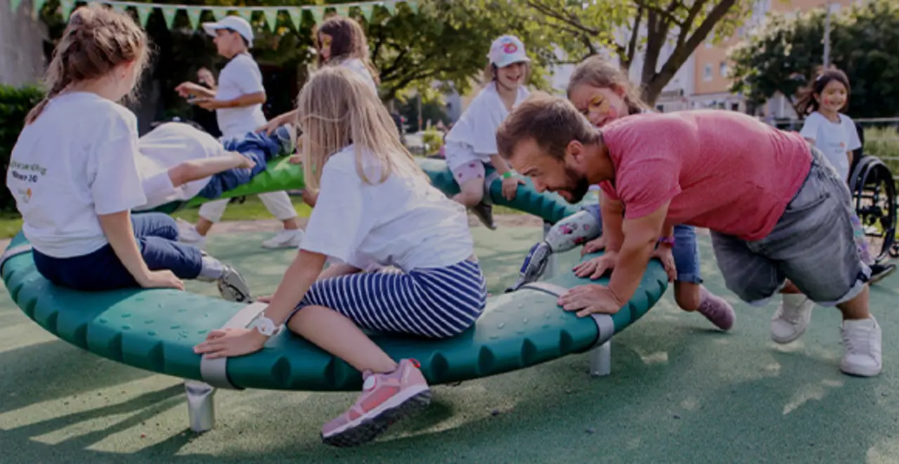 Mehrere Kinder sitzen auf einem inklusiven „Supernova“ Drehring. Matthias Mester schiebt ihn an.