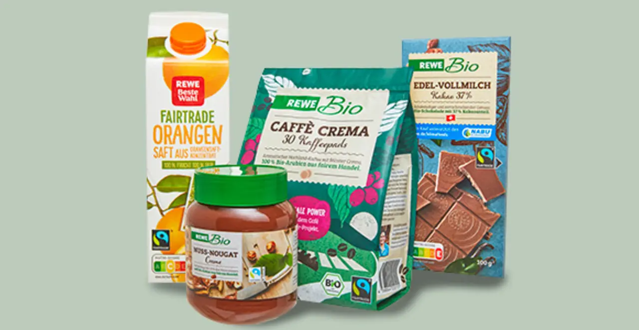 Mehrere Fairtrade Produkte: REWE Beste Wahl Fairtrade Orangensaft, REWE Bio Nuss-Nougat-Creme, REWE Bio Caffè Crema und eine Tafel REWE Bio Schokolade Edel-Vollmilch.  