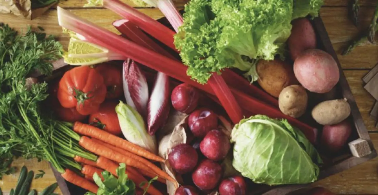 Vielfältiges regionales Obst und Gemüse liegt auf einem Holztisch.