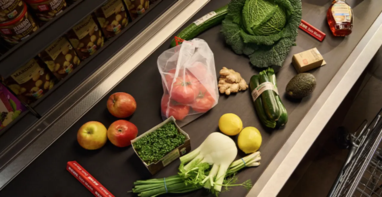 Verschiedene REWE Eigenmarken-Produkte in optimierten Verpackungen liegen auf einem Kassenband.