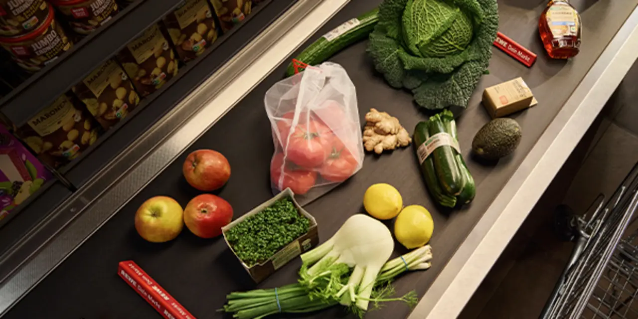 Verschiedene REWE Eigenmarken-Produkte in optimierten Verpackungen liegen auf einem Kassenband.